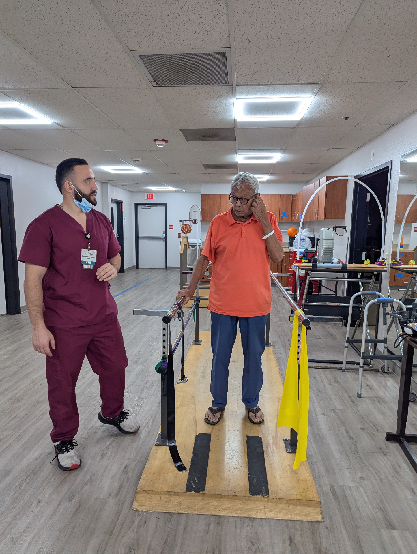 Physical therapist supporting an older adult during a walking exercise